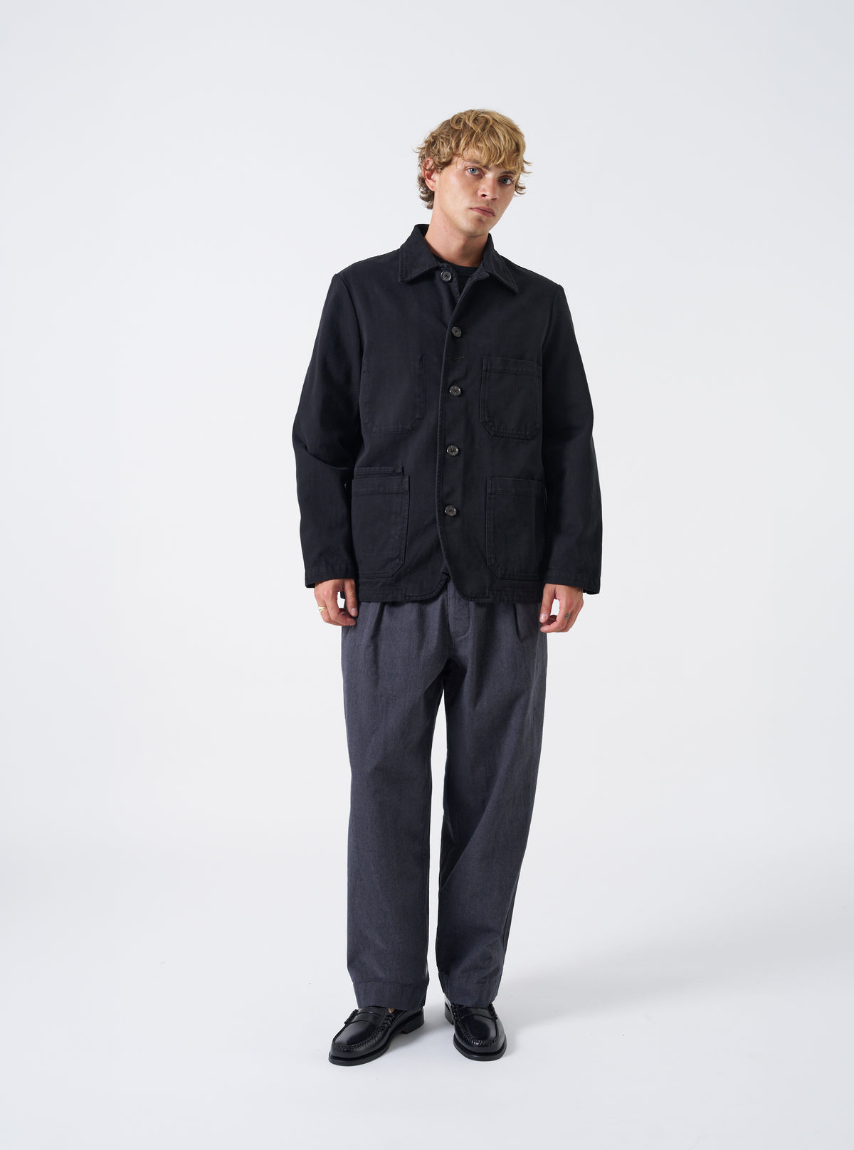 A male model wears the Black Dexter Twill OG Bakers Chore Jacket buttoned up, captured against a plain white studio background. The shot highlights the relaxed fit, functional patch pockets, and classic chore coat style.