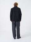 A male model wears the Black Dexter Twill OG Bakers Chore Jacket unbuttoned over a shirt, standing against a neutral studio background. The view details the open front layer, collar, and comfortable overall silhouette.