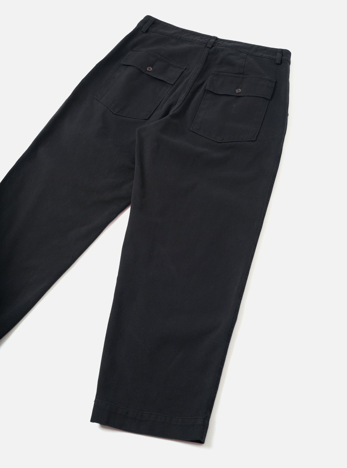 Back view of the Black Dexter Twill Grad Chino presented against a clean off-white background. The shot highlights the military fatigue inspired back pockets, rear seam construction, and organic cotton twill fabric.