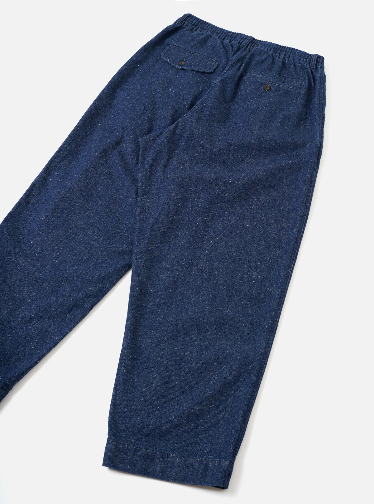 Back view of the Indigo Future Denim Oxford Pant set against a clean white backdrop. The photo highlights the rear pockets, gentle taper toward the leg openings, and rich indigo denim fabric texture.