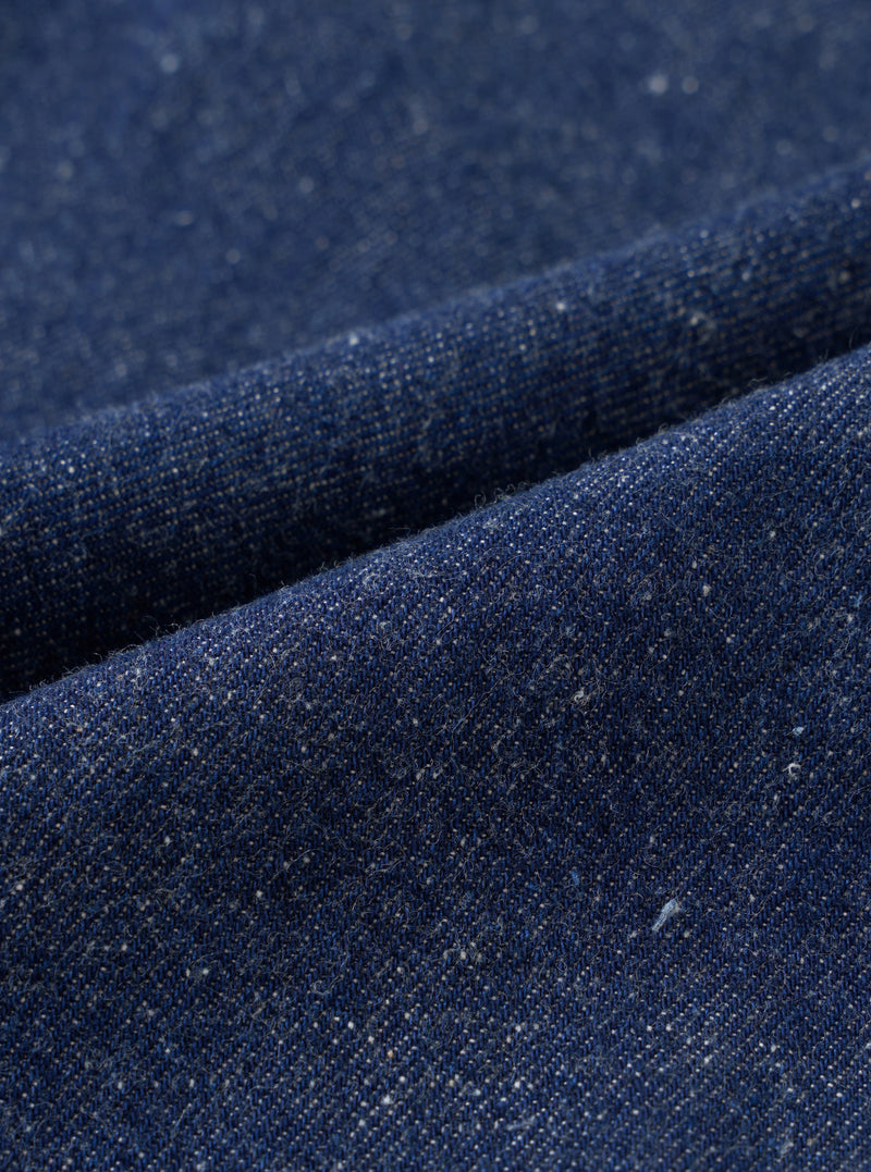 A close-up fabric swatch shot showing the rich indigo color and slubby nep surface texture of the recycled and organic cotton fabric used for the Indigo Future Denim Oxford Pant. The frame is filled with fabric.
