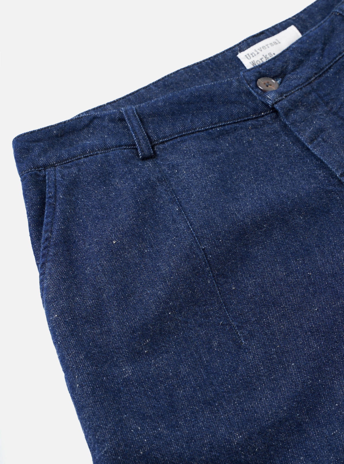 Detailed close-up view of the Indigo Future Denim Grad Chino set against a white studio background, highlighting the ticket pocket construction, belt loops, and organic denim surface texture.