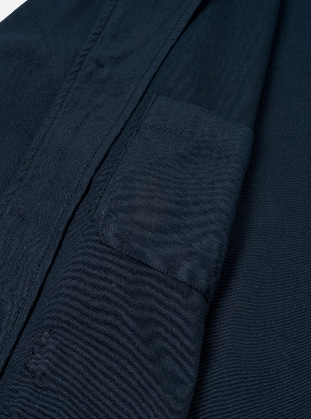 A close-up detail shot of the Navy Slub Sateen Ives Jacket against an off-white background, highlighting the collar structure, contrast buttons, front chest patch pocket, and slub sateen cotton fabric weave.