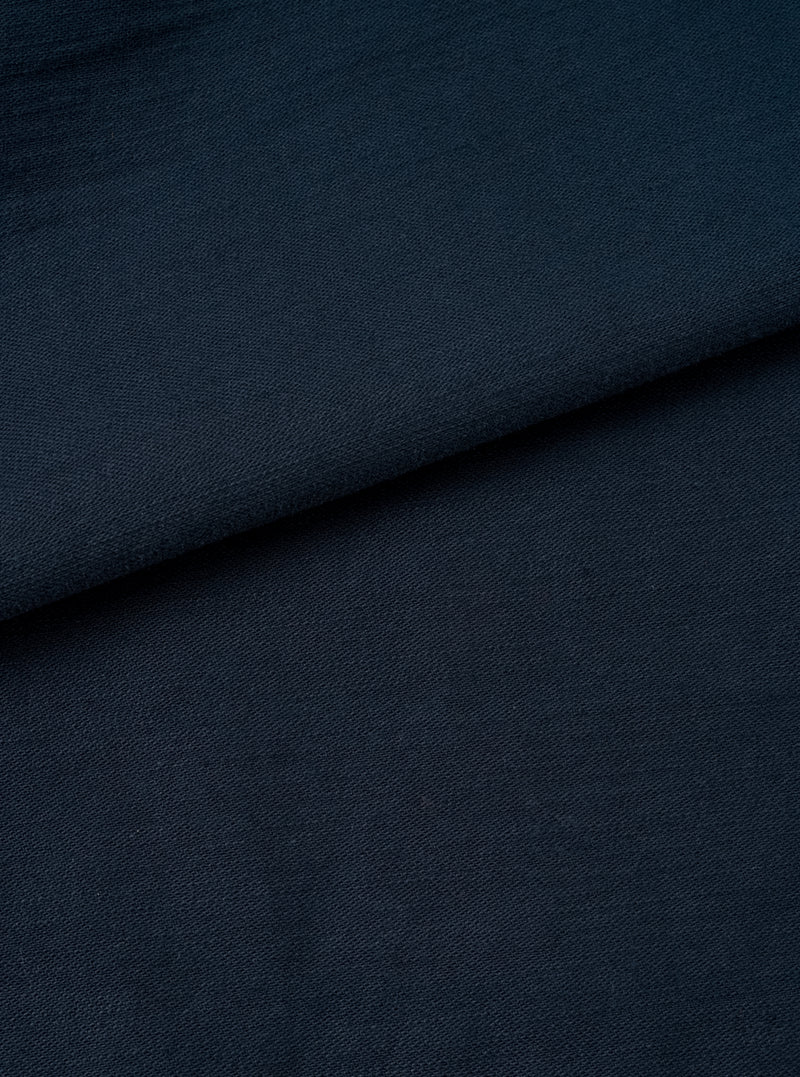 A detailed close-up fabric swatch revealing the slub sateen weave in dark navy blue. The image fills the entire frame, highlighting the rich color, fine surface texture, and cotton material details.