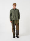 A male model wears the Olive Slub Sateen Ives Jacket over a top, standing in a front-facing full-length studio shot against a plain neutral background, showcasing the relaxed boxy silhouette and fit.