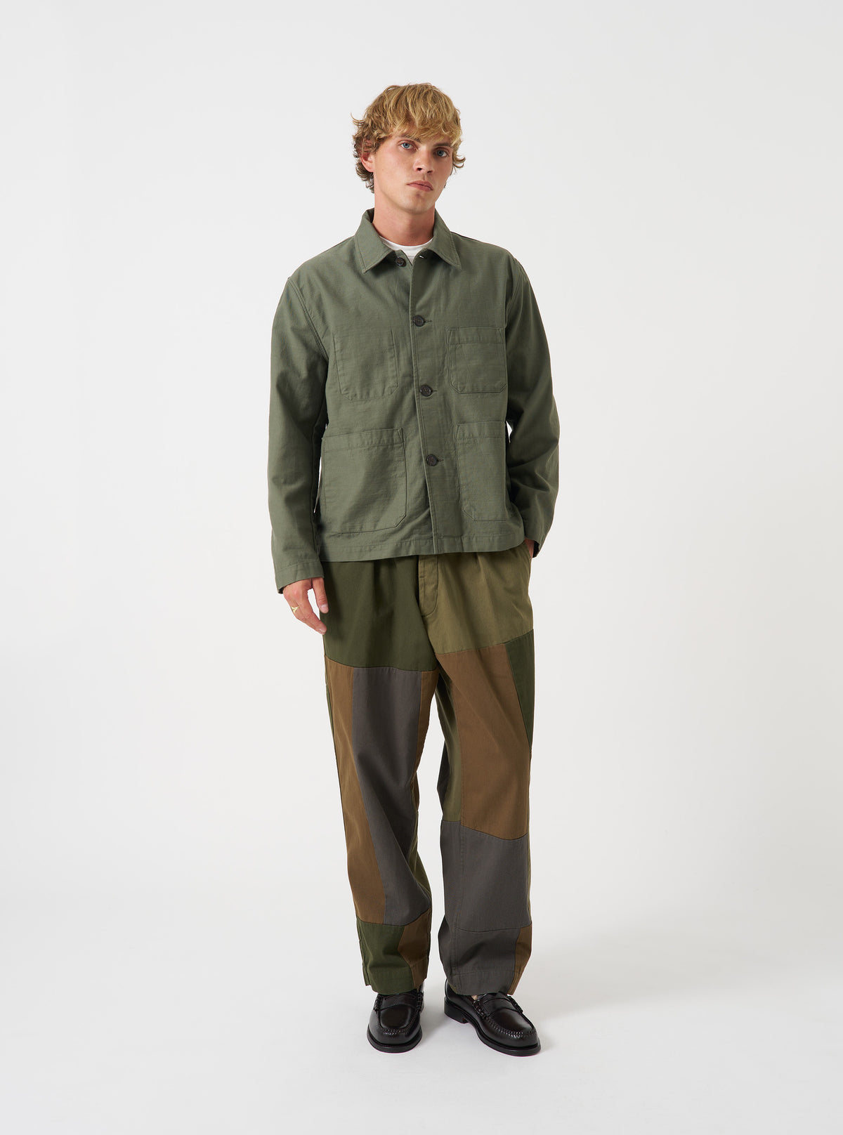 A male model wears the Olive Slub Sateen Ives Jacket over a top, standing in a front-facing full-length studio shot against a plain neutral background, showcasing the relaxed boxy silhouette and fit.