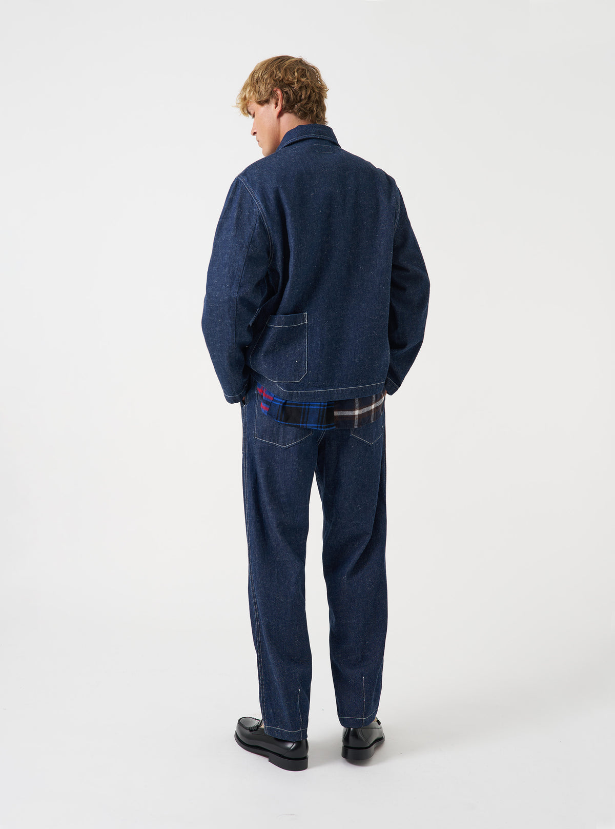 A male model wears the Indigo Future Denim Ives Jacket, posed against a plain off-white studio background. The shot highlights the rich indigo denim fabric, classic collar construction, utility chest pockets, and relaxed tailored fit.