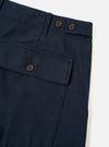 Angled studio shot of the Navy Slub Sateen Loose Fatigue Pant on a neutral off-white background. The composition emphasizes the distinct slub sateen cotton weave, side pocket entry, precise stitching details, and classic utility trouser style.