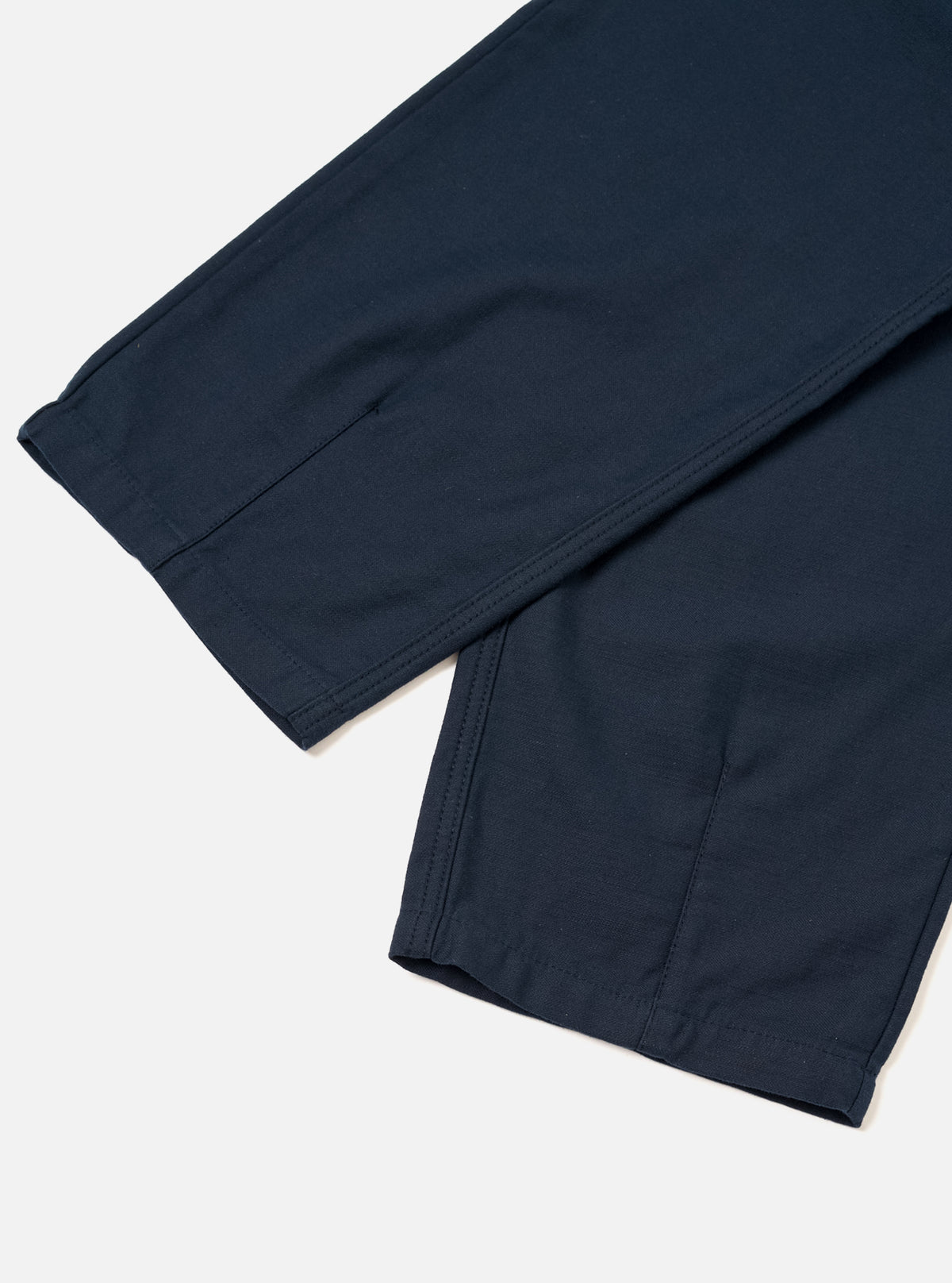 Detailed close-up image showing the construction and waist detail of the Navy Slub Sateen Loose Fatigue Pant against a plain backdrop. The image emphasizes the textured navy cotton fabric, belt loops, sturdy button closure, and pocket seams.