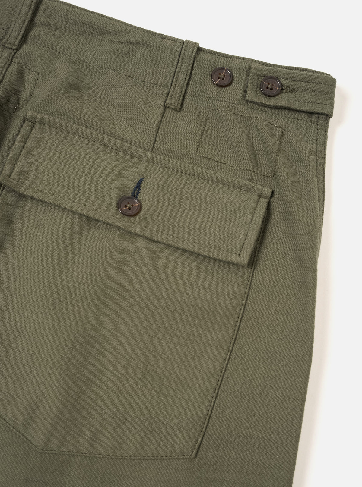 Angled product view of the Olive Slub Sateen Loose Fatigue Pant set against a plain light studio backdrop. The shot showcases the soft olive green tone, side seam pocketing, fine fabric texture, and loose casual fit of the garment.