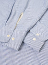 Angled product shot of the Blue Montgomery Stripe Station Shirt against a plain light background. The composition highlights the blue stripe alignment along the side seams, clean buttoned cuffs, crisp collar fold, and relaxed fit.