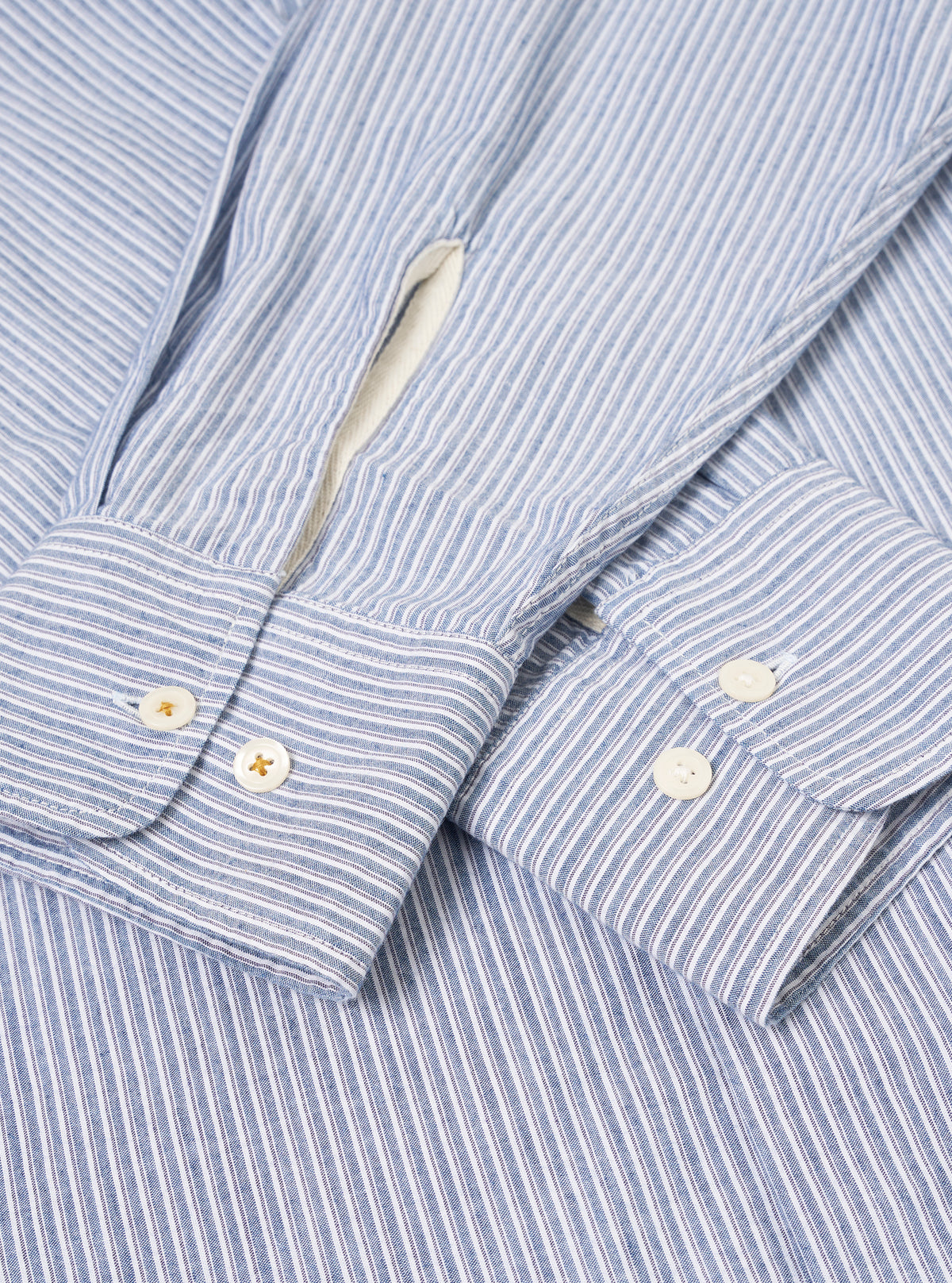 Angled product shot of the Blue Montgomery Stripe Station Shirt against a plain light background. The composition highlights the blue stripe alignment along the side seams, clean buttoned cuffs, crisp collar fold, and relaxed fit.