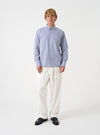 A male model wears the Navy Queens Cotton Patched Shirt buttoned up against a clean studio background. The full front shot highlights the button-down collar, patch pocket, and subtle striped patchwork pattern.