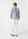 A male model wears the Navy Queens Cotton Patched Shirt styled casually against a neutral backdrop. Captured in a three-quarter pose, the shot showcases the relaxed silhouette and contrasting stripe placements.
