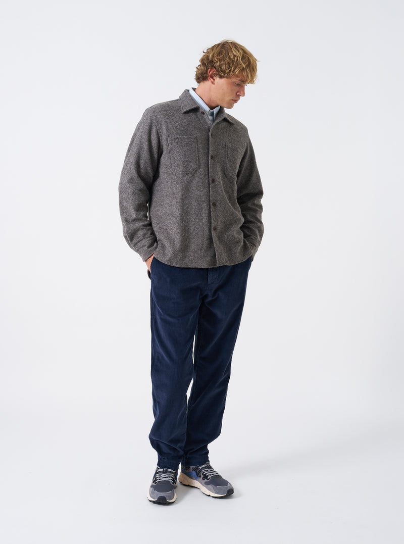 A male model poses wearing the Mid Brown Dam Marl Work Shirt against a neutral white studio background. The full front shot highlights the warm brown marl texture, camp collar, and casual silhouette.