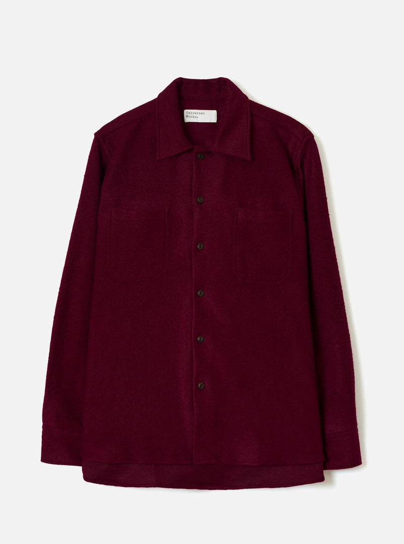 Front view of the Dark Red Dam Marl Work Shirt displayed against a plain off-white background. The shot highlights the one-piece collar, two chest flap pockets, button front closure, and curved hem silhouette.