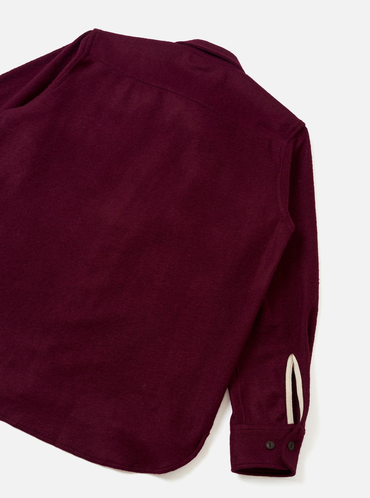An angled view of the Dark Red Dam Marl Work Shirt set against a plain light background. The image emphasizes the soft marl wool-blend texture, structured sleeve cuffs, and clean shoulder seam construction.