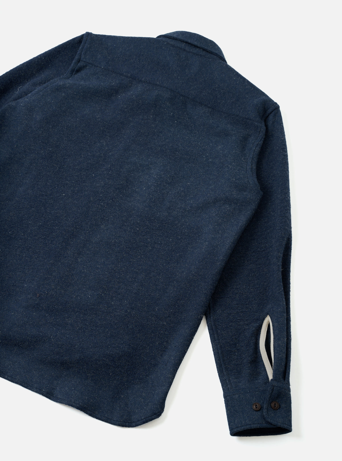 An angled view of the Navy Dam Marl Work Shirt set against a plain light background. The image showcases the structured fit, sleeve button cuffs, and deep navy heathered knit fabric detail.