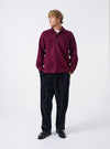 A male model wears the Dark Red Dam Marl Work Shirt over a basic top, standing against a neutral studio background. The full-length shot highlights the relaxed fit, front chest pockets, and rich red color.