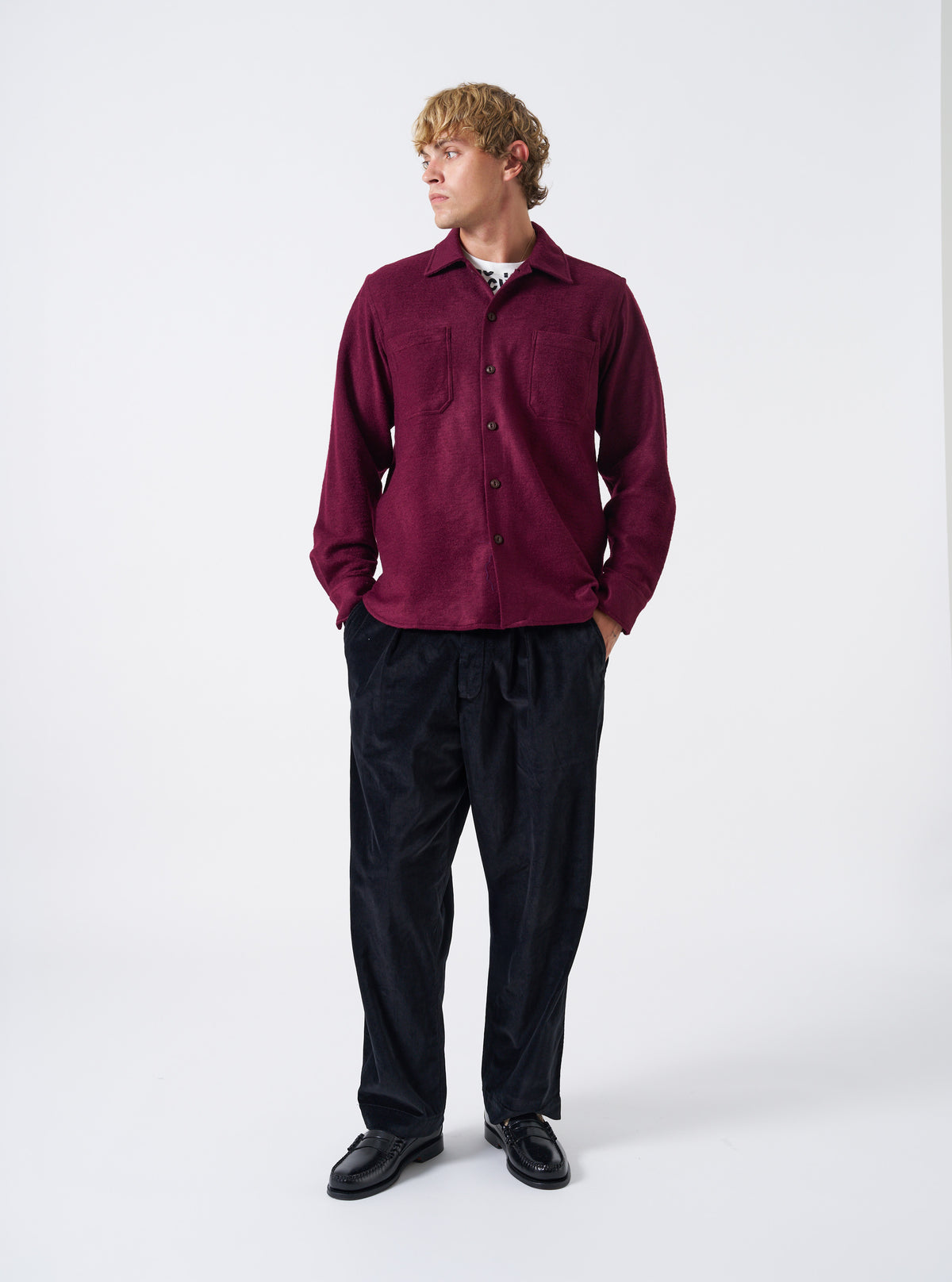 A male model wears the Dark Red Dam Marl Work Shirt over a basic top, standing against a neutral studio background. The full-length shot highlights the relaxed fit, front chest pockets, and rich red color.