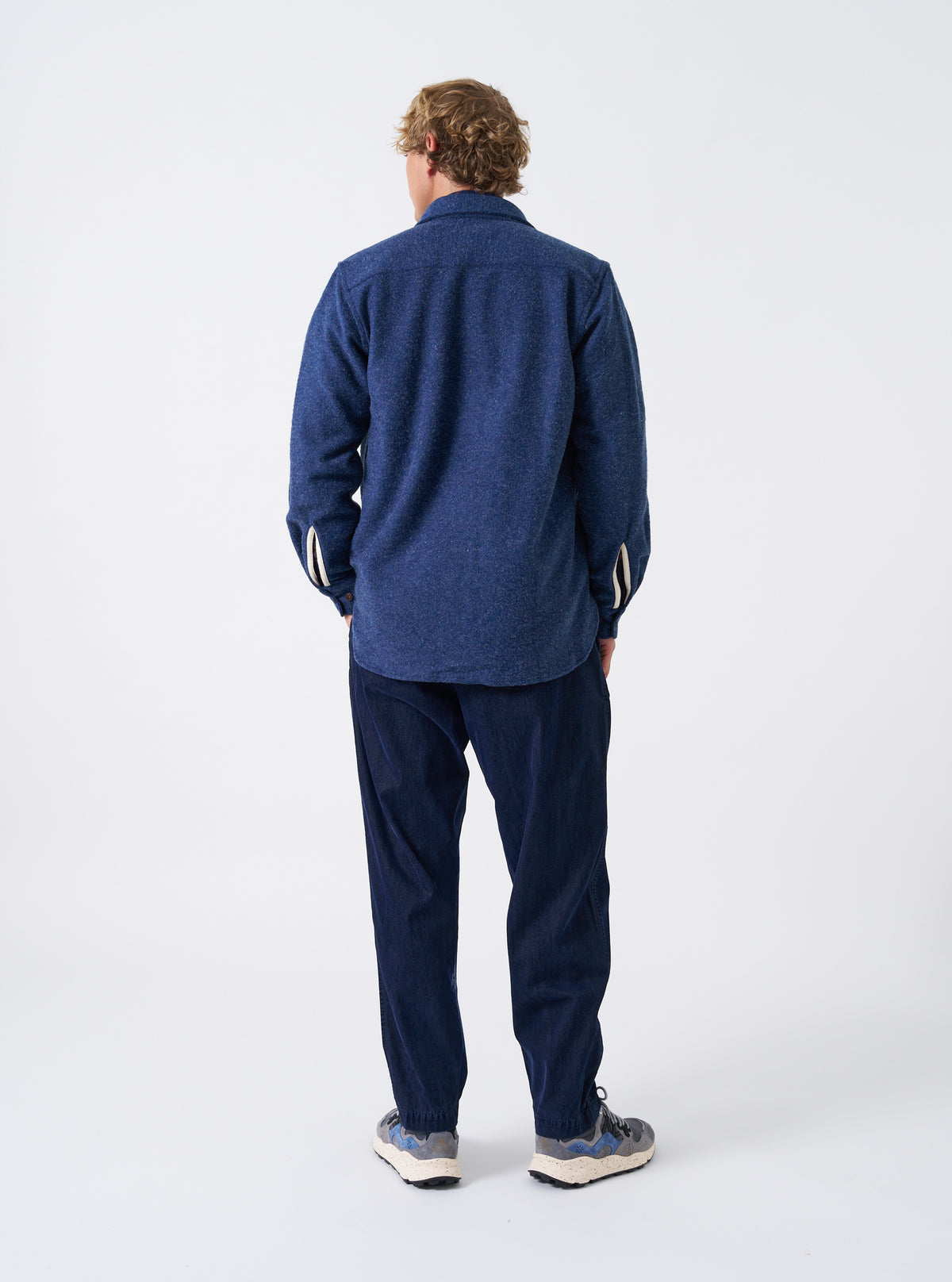 A male model is featured wearing the Navy Dam Marl Work Shirt from the back against a white background. The shot highlights the clean shoulder construction and straight hem of the dark navy garment.