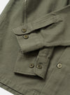 A side profile shot of the Olive Slub Sateen Fatigue Shirt displayed against a simple white backdrop. The view highlights the sleeve construction, cuff details, and relaxed fit of the olive overshirt.