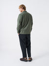 A male model is pictured from the back wearing the Olive Slub Sateen Fatigue Shirt against a plain white backdrop. The shot details the comfortable fit across the shoulders and the clean rear hem.