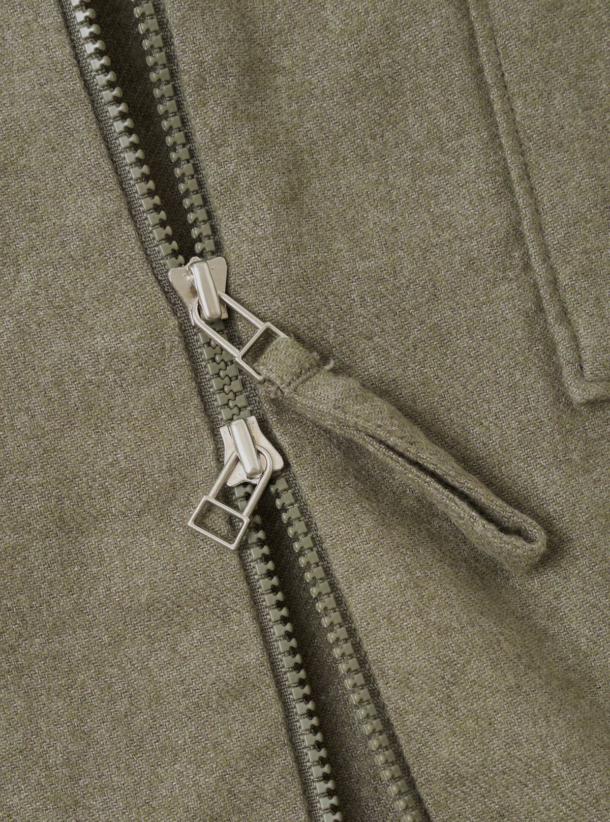 A detailed close-up view of the Olive Monty Cotton Tencel Zip Shirt on a plain white studio background, emphasizing the front zip fastening, collar stitching, and textured fabric weave.