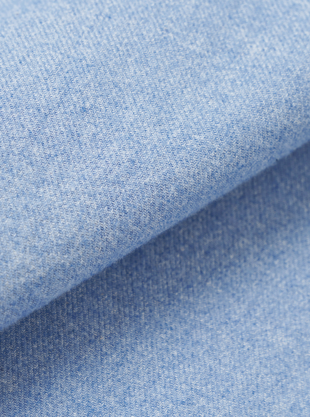 A full-frame fabric swatch closeup displaying the subtle weave pattern, soft cotton-tencel texture, and sky blue color of the material from the Sky Blue Monty Cotton Tencel Zip Shirt.