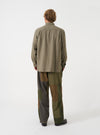 A male model wears the Olive Monty Cotton Tencel Standard Shirt unbuttoned over a t-shirt, captured against a simple studio backdrop to detail the relaxed fit and casual layered styling.