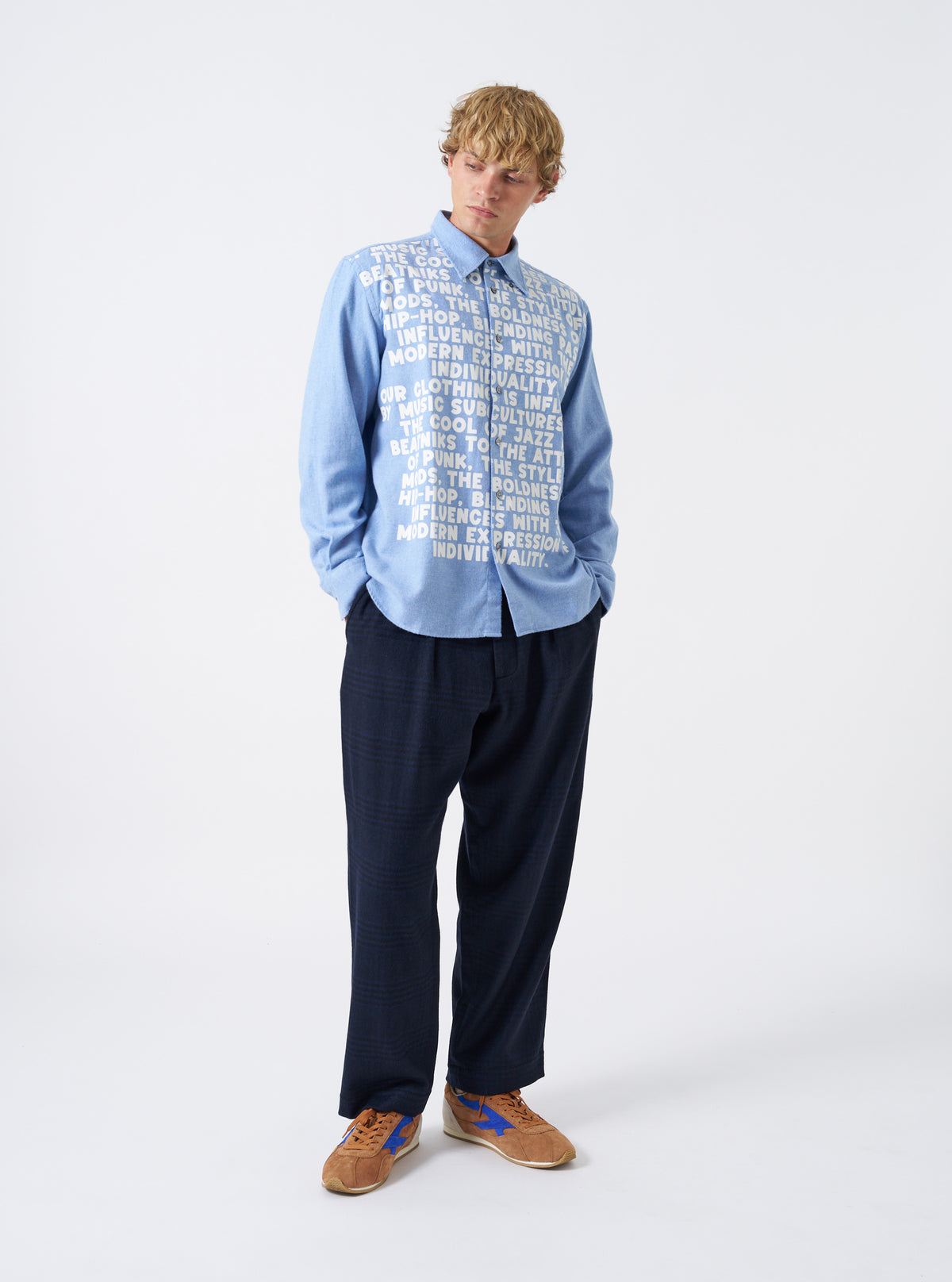 A male model stands against a neutral studio backdrop wearing the Sky Blue Monty Cotton Tencel Standard Shirt buttoned up. The full-length front view highlights the fit, collar shape, and relaxed silhouette.