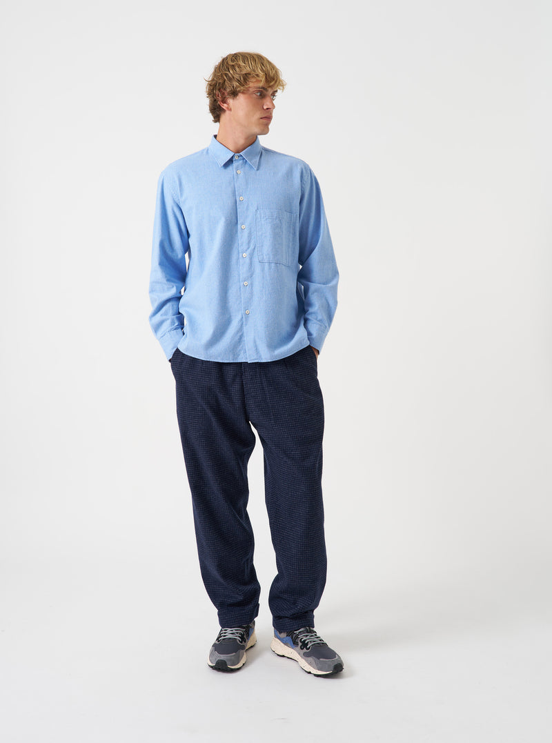 A male model wears the Blue Brushed Flannel Square Pocket Shirt against a plain studio background. The front shot emphasizes the classic collar, front button closure, and square chest pockets on the textured fabric.