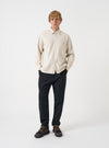 A male model wears the Ecru Brushed Flannel Square Pocket Shirt standing against a plain neutral background. The full front view highlights the light ecru tone, chest pockets, and button-up closure.