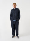 A male model stands against a studio backdrop wearing the Navy Airline Flannel Travail Overshirt buttoned up. The front shot highlights the pointed collar, spacious front pockets, and durable dark blue fabric.