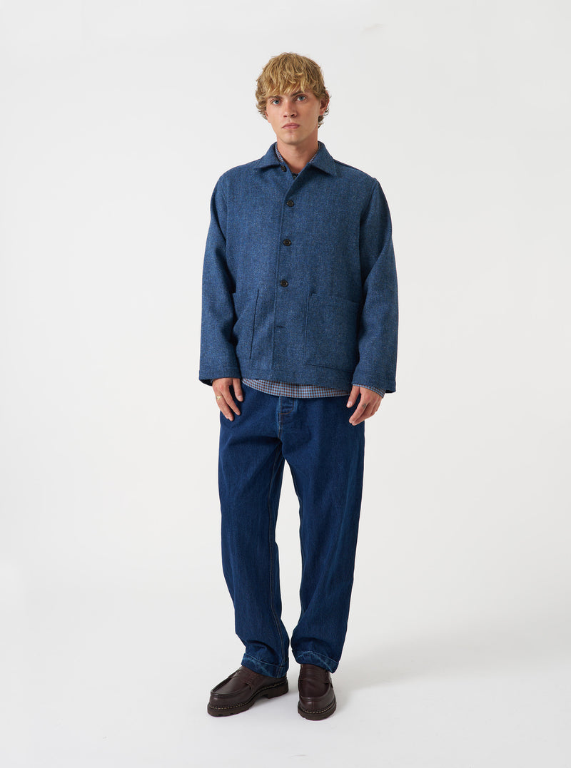 A male model wears the Blue Harris Tweed Easy Jacket buttoned up while standing against a neutral studio backdrop. The front shot highlights the jacket's structured fit, tailored lapels, and practical front pockets.
