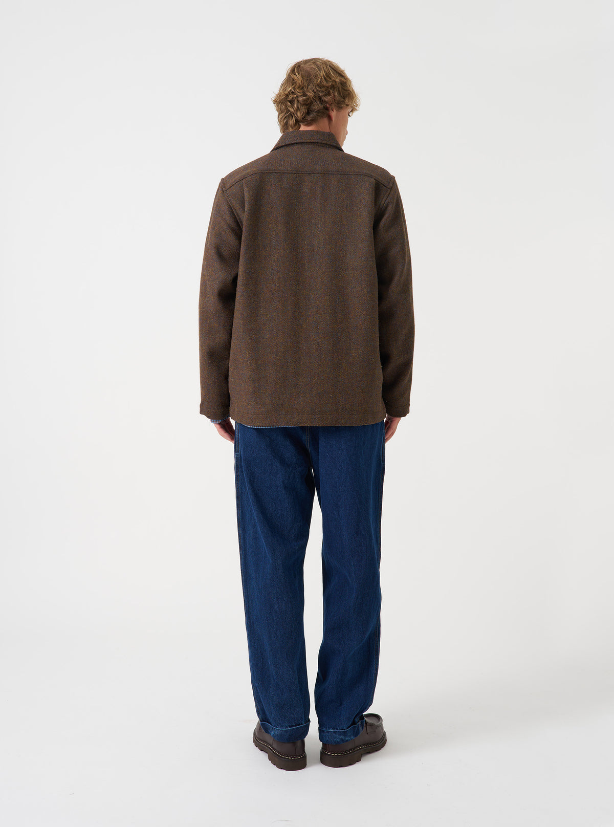 A male model stands in a studio setting wearing the Brown Harris Tweed Easy Jacket in a side profile pose. The picture highlights the shoulder cut, sleeve length, and comfortable textured fit.