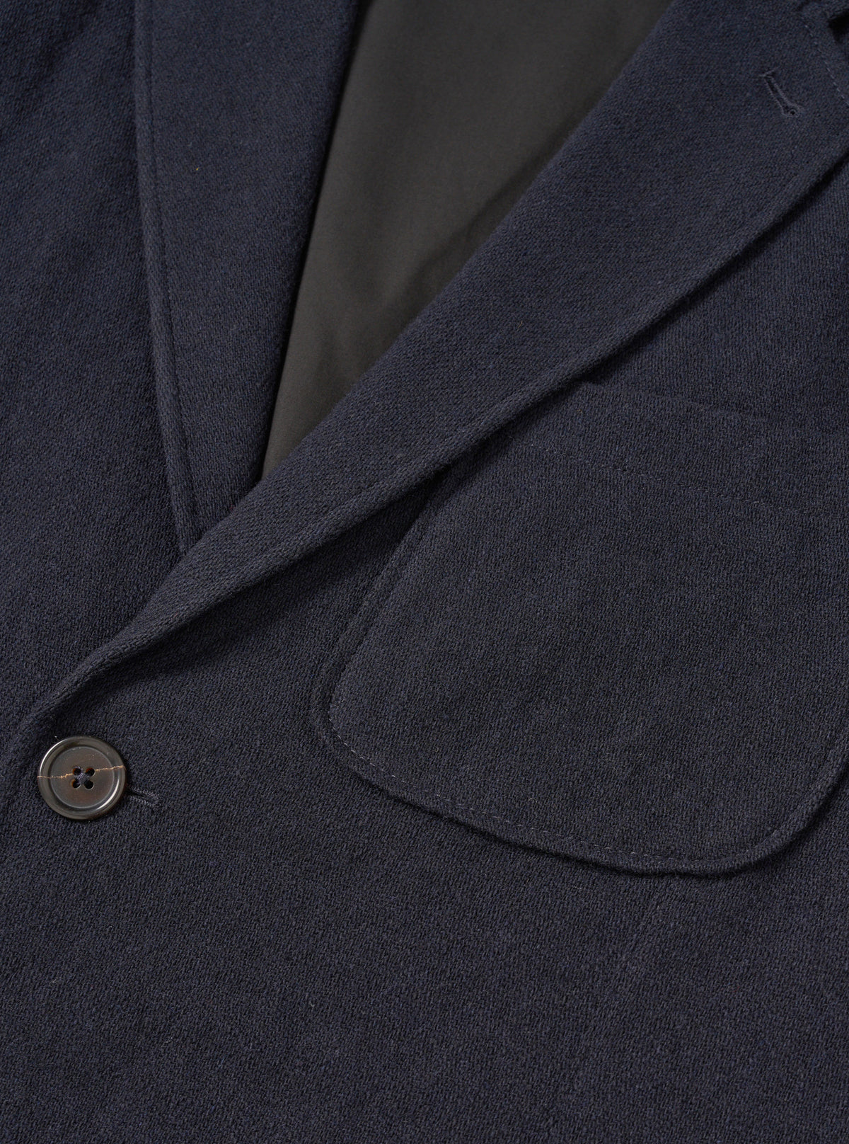 A male model wears the Dark Navy Robin Wool Mix Two Button Jacket styled over a casual outfit against a plain light studio backdrop, demonstrating the relaxed tailor fit, wide lapels, and patch pockets.