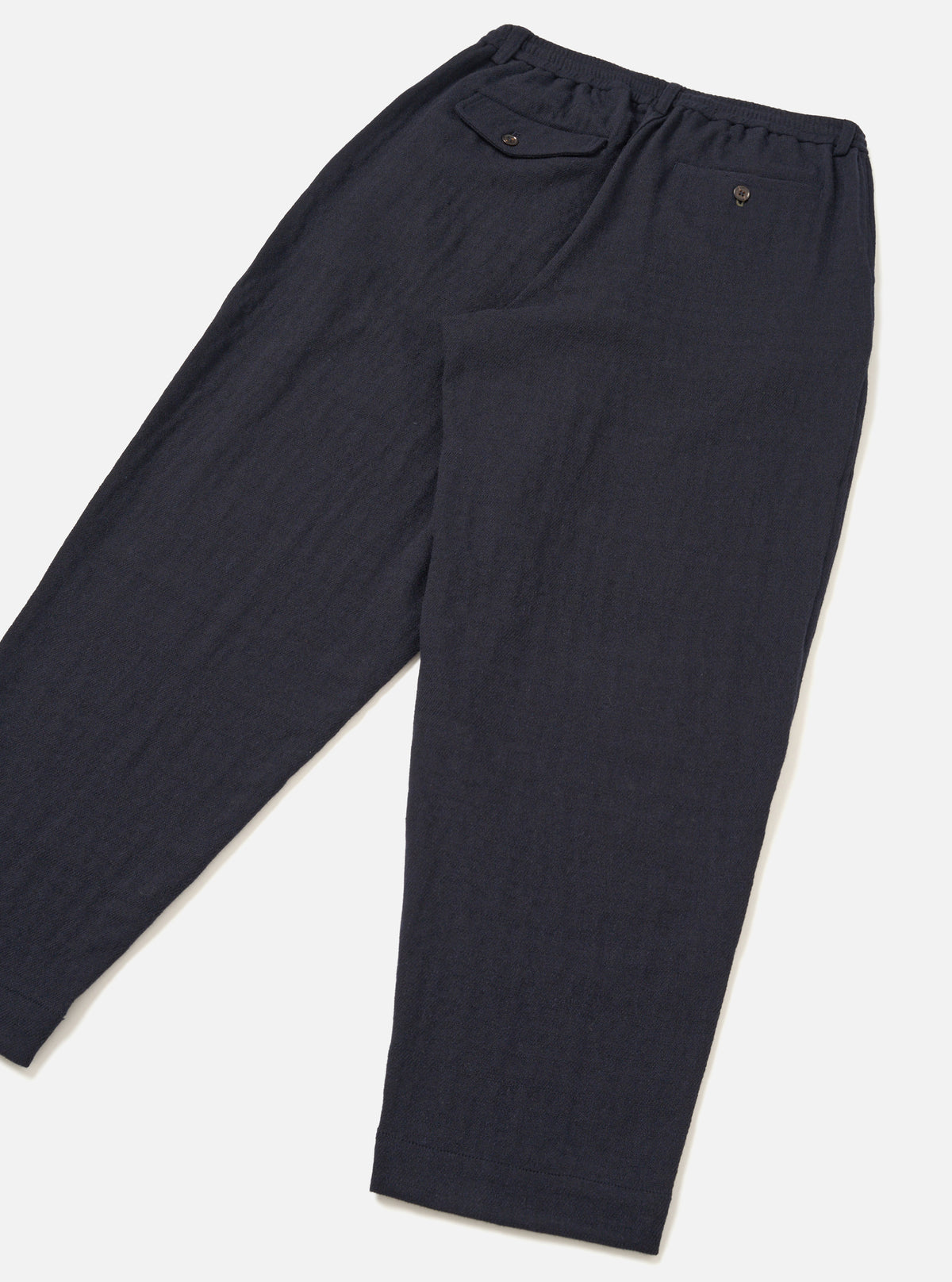 Rear view of the Dark Navy Robin Wool Mix Pleated Track Pant set against a plain off-white background. The shot highlights the relaxed fit, back welt pockets, and clean hem construction.