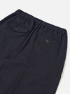 A male model wears the Dark Navy Robin Wool Mix Pleated Track Pant with a casual top, standing against a neutral studio backdrop. The full-length shot shows the tapered leg and loose fit.