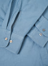 A male model wears the Mid Blue R.Oxford Lazy Day Shirt unbuttoned over a plain t-shirt, standing against a neutral studio background. The shot highlights the relaxed fit and casual style.