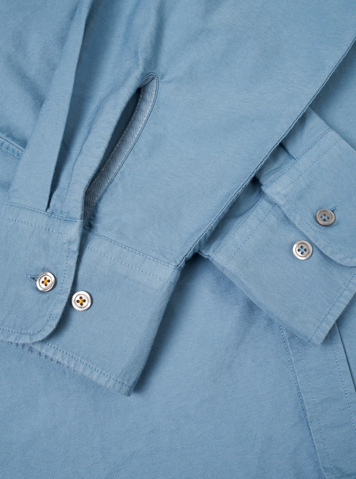 A male model wears the Mid Blue R.Oxford Lazy Day Shirt unbuttoned over a plain t-shirt, standing against a neutral studio background. The shot highlights the relaxed fit and casual style.