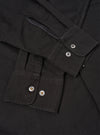 A male model wears the Black R.Oxford Lucky Shirt unbuttoned over a t-shirt against a neutral studio backdrop, demonstrating the loose fit and easy untucked style of the garment.