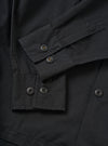 A detailed close-up shot of the Black Slub Shirting Fatigue Shirt set against a plain background. The view emphasizes the textured slub cotton fabric, neat chest pocket stitching, and front button closure details.