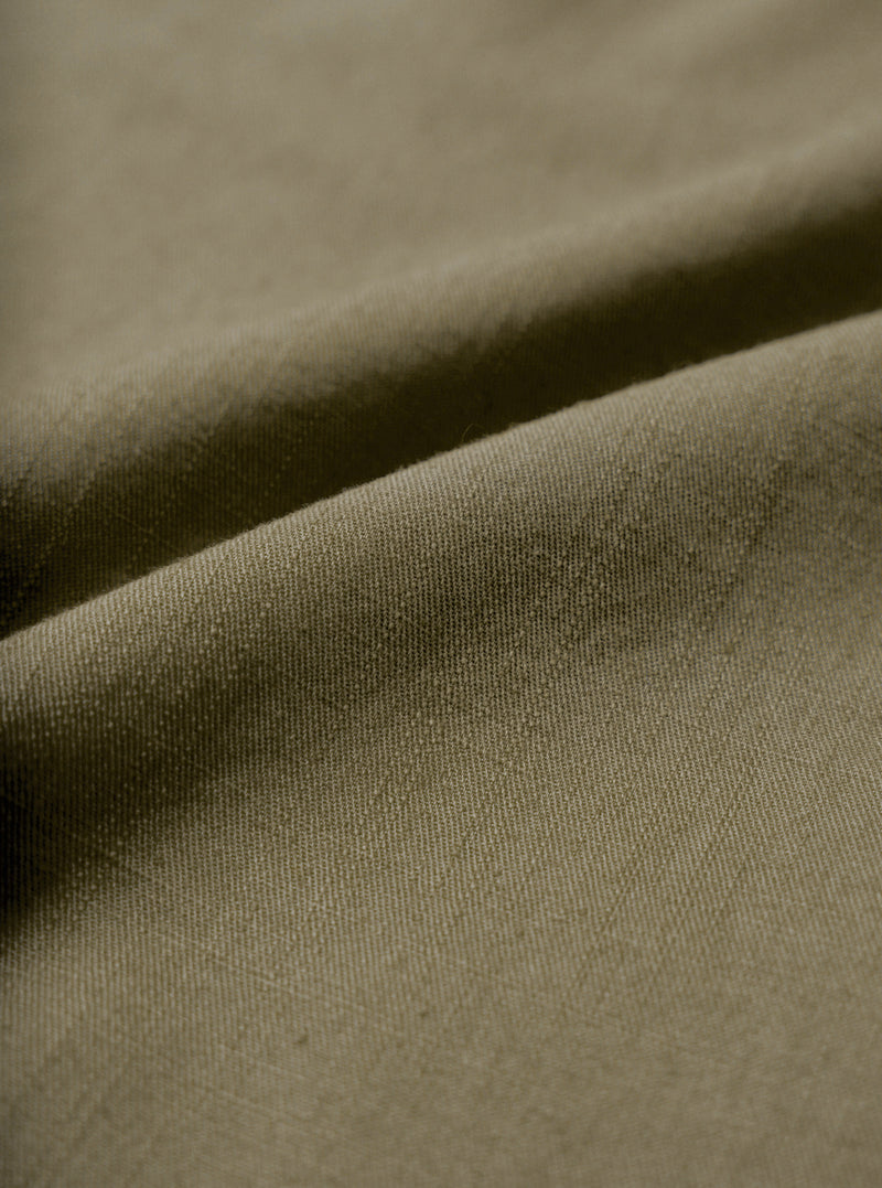A macro fabric swatch image showing the fine weave and soft slub texture of the Olive Slub Shirting Fatigue Shirt. The close-up view fills the frame to display the distinct olive green shade and cotton material structure.