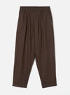 A full-length front view of a model wearing the Brown Recycled Italian Tweed Pleated Track Pant in a studio setting. The image showcases the relaxed tapered fit, drawstring waist, and warm brown tweed fabric.