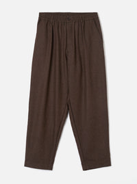 A full-length front view of a model wearing the Brown Recycled Italian Tweed Pleated Track Pant in a studio setting. The image showcases the relaxed tapered fit, drawstring waist, and warm brown tweed fabric.