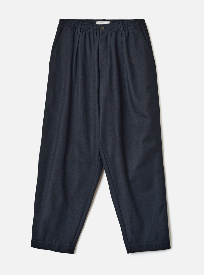 A full-length front view of a model wearing the Navy Recycled Italian Tweed Pleated Track Pant in a studio environment. The shot highlights the loose tapered cut, front pleats, and rich navy tweed finish.