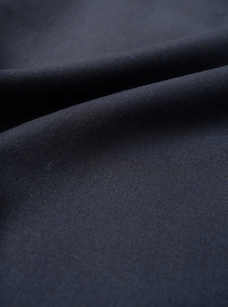 A detailed close-up fabric swatch image of the Navy Recycled Italian Tweed Pleated Track Pant on a plain white background, highlighting the rich texture, weave pattern, and subtle color depth of the navy blue tweed material.