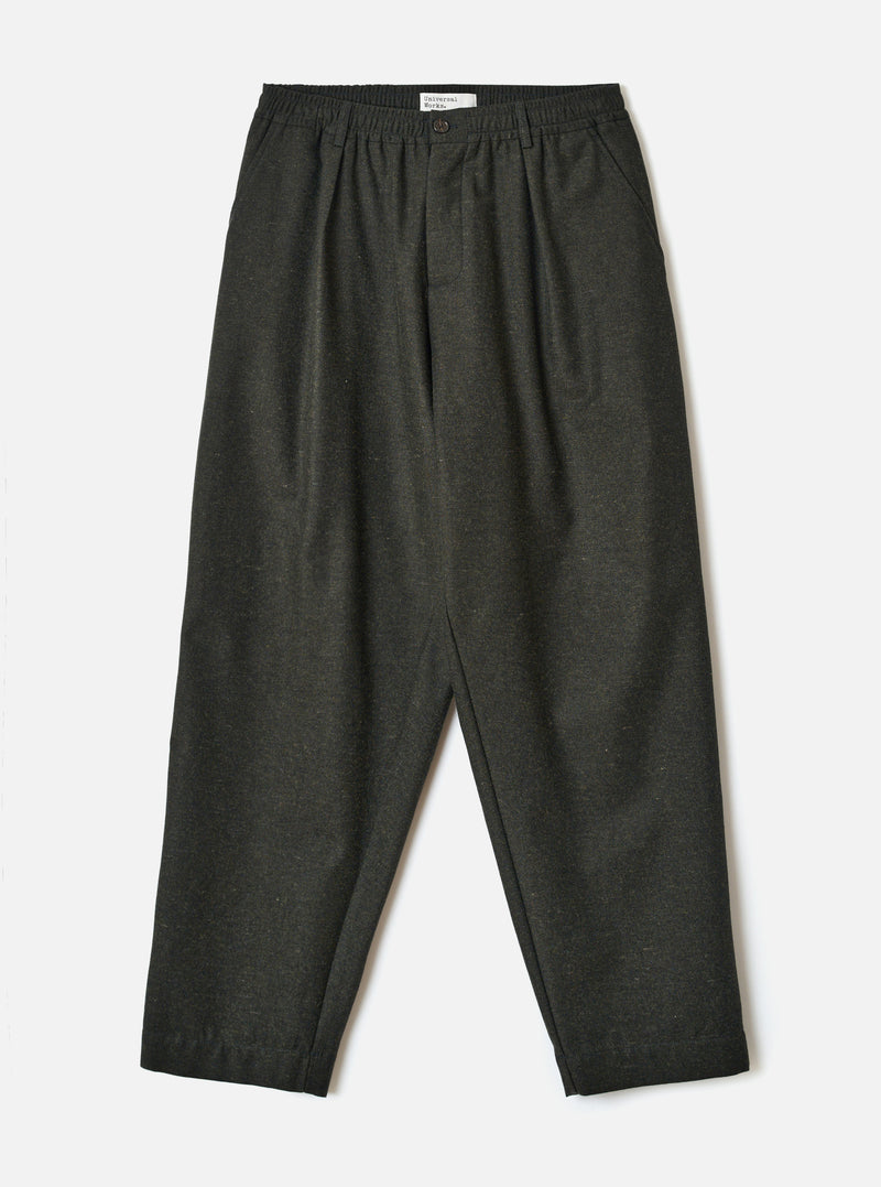A full-length front view of a model wearing the Olive Recycled Italian Tweed Pleated Track Pant against a neutral studio background. The shot highlights the loose tapered silhouette, pleated waist, and olive green tweed finish.