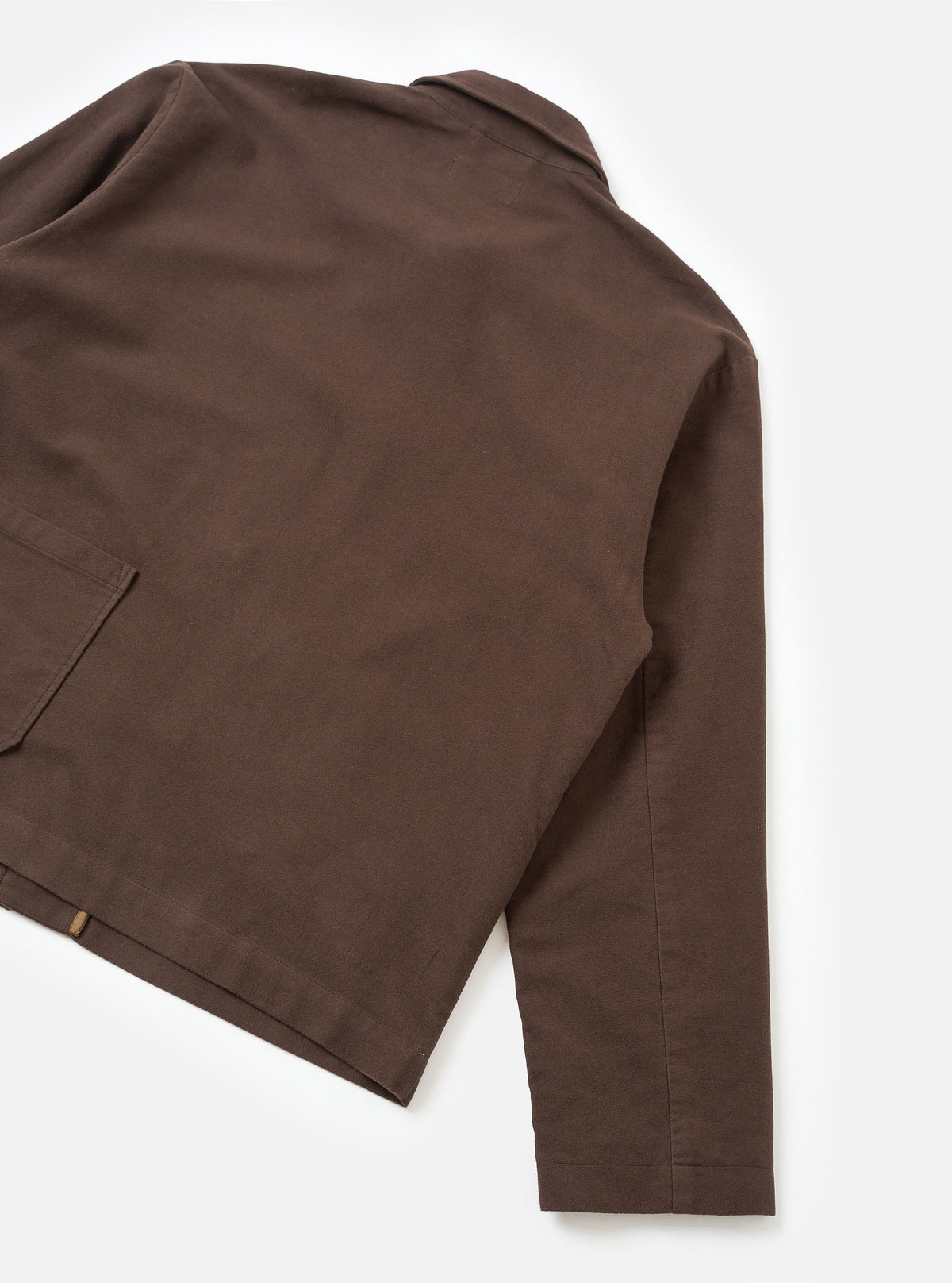 A back view of a model wearing the Brown Comfort Moleskin Ives Jacket set against a plain studio backdrop, highlighting the clean stitching, relaxed silhouette, and smooth brown cotton moleskin finish.